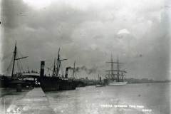 Steamships and a sailing vessel entering a lock.