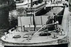 Coal-laden barge passing under a bridge.