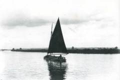 A sloop on under way on a river.