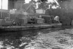 Dredger or crane barge Swanmore moored alongside on a canal or river.