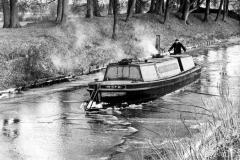 A work boat is breaking ice on a frozen canal.