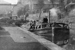 Coal laden keels are shown moored in an urban setting.