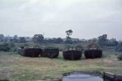 Four dumb barges hauled up on dry land.