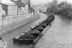 A snaking, coal laden compartment boat train.
