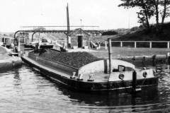 A coal laden motor barge leaving a lock.