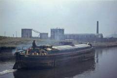 A tiller steered, unladen motor barge.