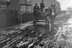 A muddy street, with a horse and cart.