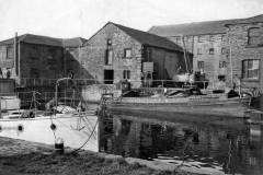 A barge alongside canal warehouses.