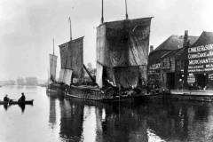 Three keels moored close to warehouses.