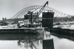 A mobile crane is positioning a canal lock gate.