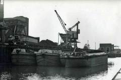 Barges moored alongside a power station.