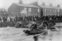 Four men racing their coggy boats.