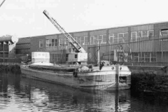 The motor barge Phyllis is moored alongside an industrial unit.