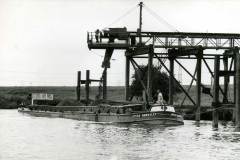 Barge Joyce Hawksley is being loaded with coal via a waterside conveyor belt and chute.