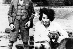 A mother, son and dog by a weir.