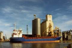 A motor vessel moored alongside silos.